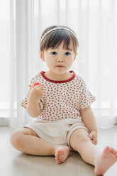 Toddler girl wearing Avauma Mellow Pop Ivory Berry Set, sitting comfortably and looking towards camera